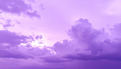 Obraz premium A stunning purple sky adorned with fluffy, soft clouds, creating a dreamy atmosphere as the sun sets, casting a warm glow across the horizon.