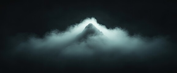 Obraz premium Mountain peak shrouded in clouds; monochrome, dark, and atmospheric, top glowing