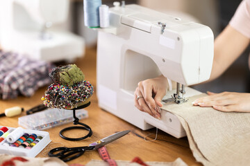 Female hands of seamstress sewing clothes on sewing machine in sewing workshop close-up