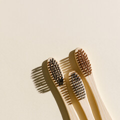 Eco friendly Bamboo toothbrushes with white bristles at sunlight with dark shadows on beige...