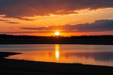 Obraz premium araffes are standing in the water at sunset with a bright orange sky