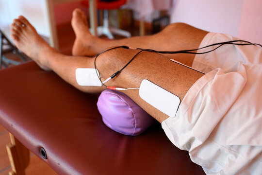 Patient receiving electrical muscle stimulation therapy on leg in clinic