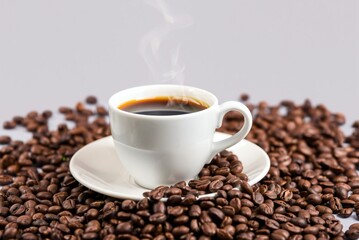 Fototapeta premium A cup of steaming coffee surrounded by coffee beans 