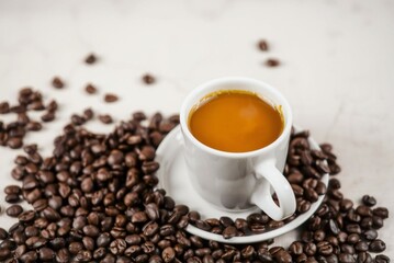 A cup of steaming coffee surrounded by coffee beans 