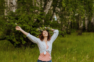 Obraz premium Happy Slavic woman with wildflower wreath celebrating Ivan Kupala in countryside