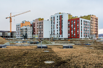 Fototapeta premium Construction of a residential complex. View of the construction site. Construction of a modern multi-apartment residential building. New unfinished building with apartments. Tower crane near the house