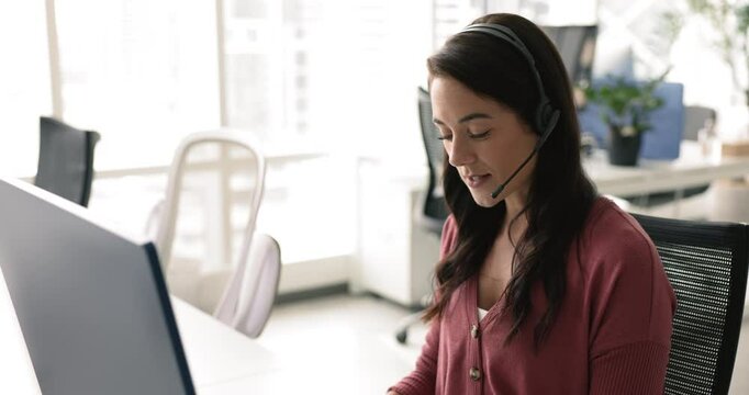 Happy Latin customer support service operator woman in headset giving consultation, instruction to client, talking on audio call at desktop monitor, speaking, listening, speaking at microphone