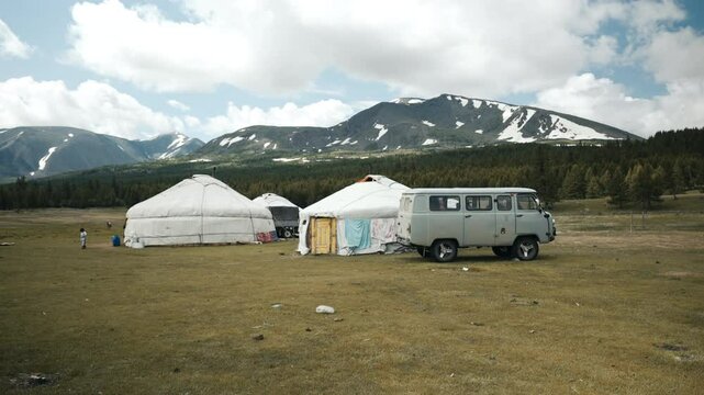 Wide-angle static shot of Khoron Lake in Mongolia on a sunny morning, capturing daily life with people, animals and gers