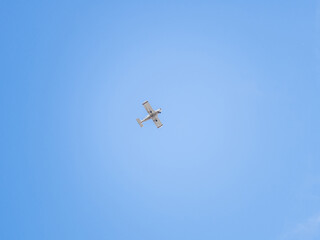 Small ultralight airplane with overhead wing and single propeller flying in sunset sky.