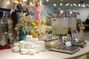A series of colorful, fruit-infused water dispensers, flanked by pineapples and coconuts, creating a tropical refreshment scene
