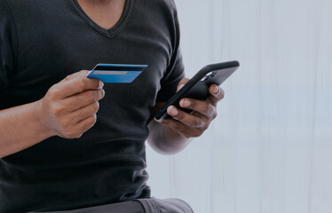 Businessman holding credit card and using touchscreen smartphone for online shopping while making orders in the hotel or home office. Business, technology, ecommerce and online payment concept.