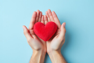 Obraz premium two hands holding a red heart on a blue background
