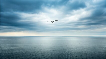 Obraz premium A solitary bird flies over a calm sea under a dramatic sky, highlighting the tranquility of nature.