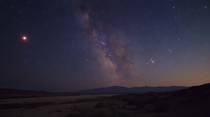 Night sky panorama with milky way and moon over desert landscape.