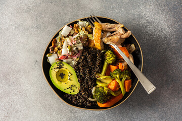 Nutritious, wholesome breakfast featuring quinoa, avocado, roast chicken, and roasted vegetables like sweet potato, zucchini, and broccoli, complemented with a fresh cabbage and radish salad