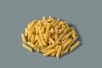 Top view of a raw italian durum wheat penne lisce pasta against a grey background , copy space . Raw dry mostaccioli penne lisce pasta , high-resolution  .