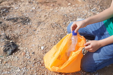 volunteering and ecology. faceless image of teenage boy picking up plastic garbage from the ground.