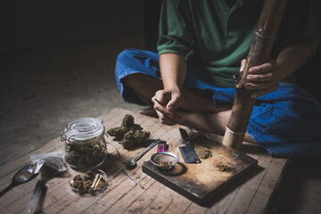 A person man sits alone in a dark room smoking marijuana, Drug addict man or drug dealer prepares heroin. international Day against Drug Abuse and Illicit Trafficking