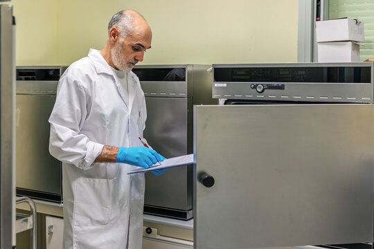 Laboratory technician recording data in front of a Memmert drying oven