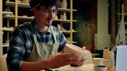 Caucasian man potter teacher artist blogger influencer craftsman decorator ceramics designer showing bowl earthenware handmade clay modeling craft workshop talk video call laptop online pottery class