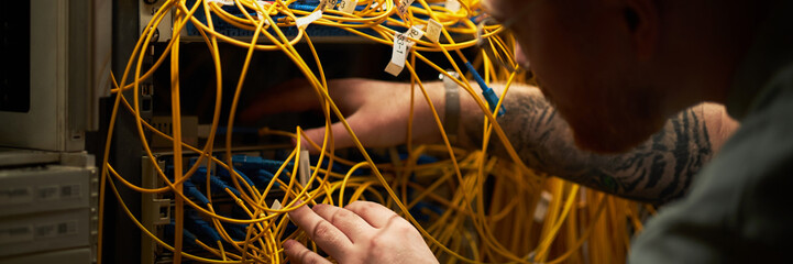 Technician managing intricate network cables inside a server rack, focusing on organizing and connecting crucial Ethernet wires without losing focus
