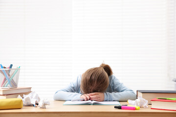 Tired little girl doing homework at table indoors