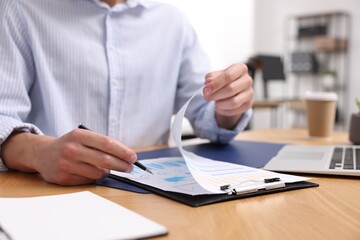 Fototapeta premium Man with papers working at wooden desk in office, closeup