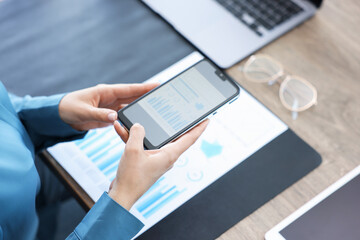 Woman taking photo of document using scanning app on smartphone at desk in office, closeup