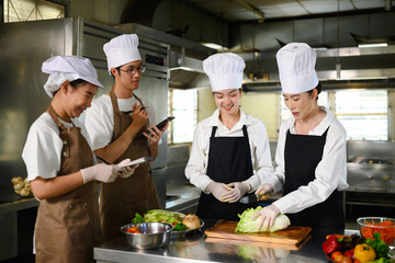 Cooking school teacher instructs students on vegetable cutting techniques in a kitchen