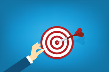 Hand holding a target, showing a goal. Red arrow hits the center. Business challenge failure and success concept.
