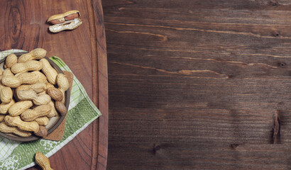 peanuts in ceramic dish on wooden background