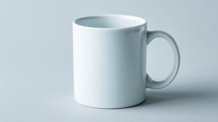 A blank white ceramic mug sits on a neutral surface, perfectly lit to showcase its smooth design, great for mockups and promotions