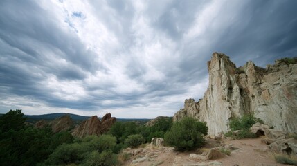 Fototapeta premium Jagged cliffs rise dramatically against a backdrop of swirling gray clouds, capturing the essence of a stormy day filled with powerful natural elements