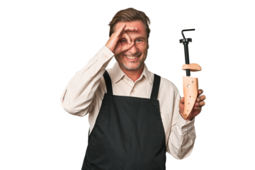 A middle-aged shoe maker excited keeping ok gesture on eye.