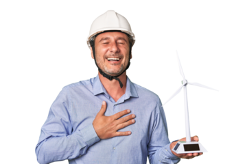 A middle-aged architect man holding a windmill model laughs out loudly keeping hand on chest.