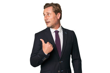A middle-aged businessman isolated points with thumb finger away, laughing and carefree.
