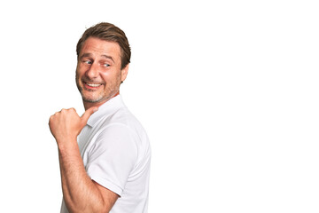 A middle-aged man isolated points with thumb finger away, laughing and carefree.