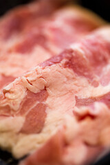 close-up image features several strips of raw beef neatly arranged in a black container at korean hotpot restaurant , showcasing the rich, marbled texture of the meat with its deep red and white hues.