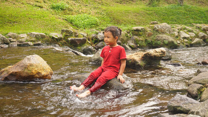 A daughter playing in a river with red clothes