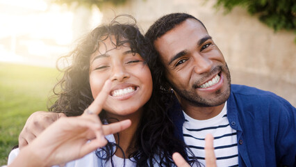 Fototapeta premium Happy African couple smiling on camera at park city. Friends enjoy summer vacation day. Youth culture, outdoors life style. Focus on man face
