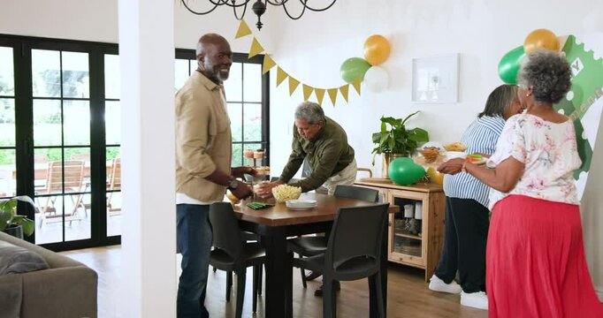 Group of happy senior multiracial, white and black male and female preparing table at retirement par