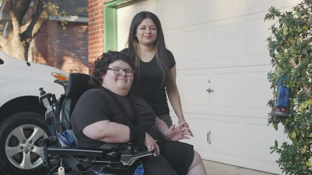 Muscular Dystrophy adolecsent in wheelchair with mom waving in front of house