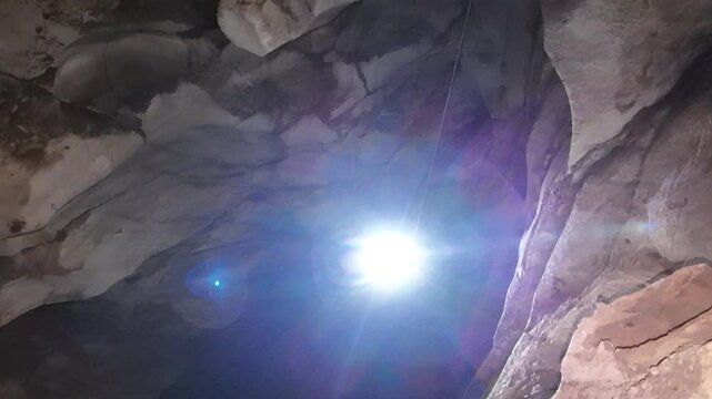 A lone caver using Single Rope Technique (SRT) descends into the pitch-black depths of Anxiety State Cave in Chiang Mai, Thailand. Adventure, mystery, and the thrill of exploration.