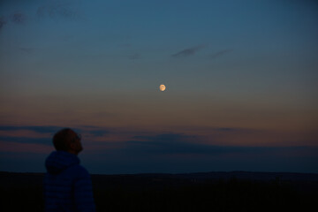 Silhouette of a man observing Moon, Milky Way stars, planets and other celestial objects from a...