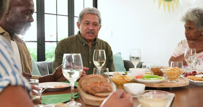 Group of happy senior multiracial, white and black male and female friends talking at retirement par
