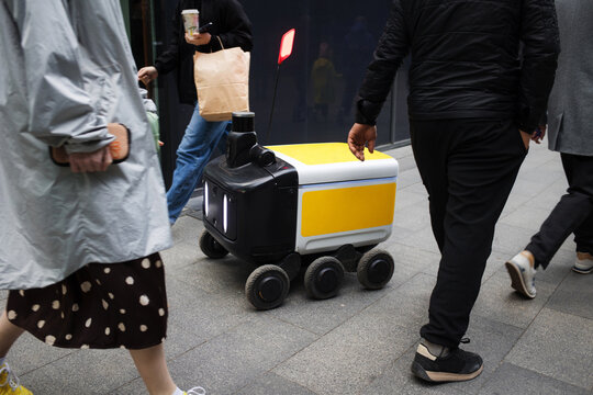innovative delivery robot delivering packages parcel along city. automaton artificial intelligence ai vehicle for delivery of food and products. rush hour on busy street of a modern metropolis