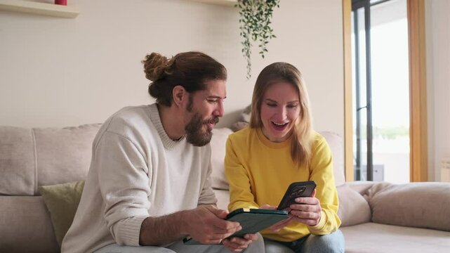 Couple comparing prices on tablet and smartphone at home