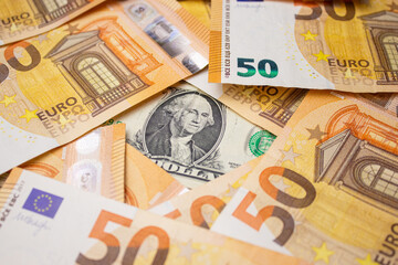 Close up of fifty euro money bills and a dollar bill in the middle background