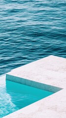 Obraz premium Minimalist poolside view of turquoise water meeting the ocean horizon in a serene setting with geometric stone architecture