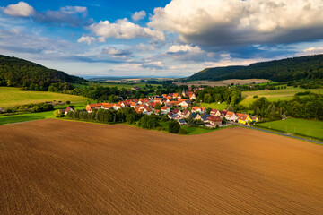 Fototapeta premium Vibrant German Village Nestled in a Valley Surrounded by Lush Greenery and Picturesque Mountains on a Bright Sunny Day